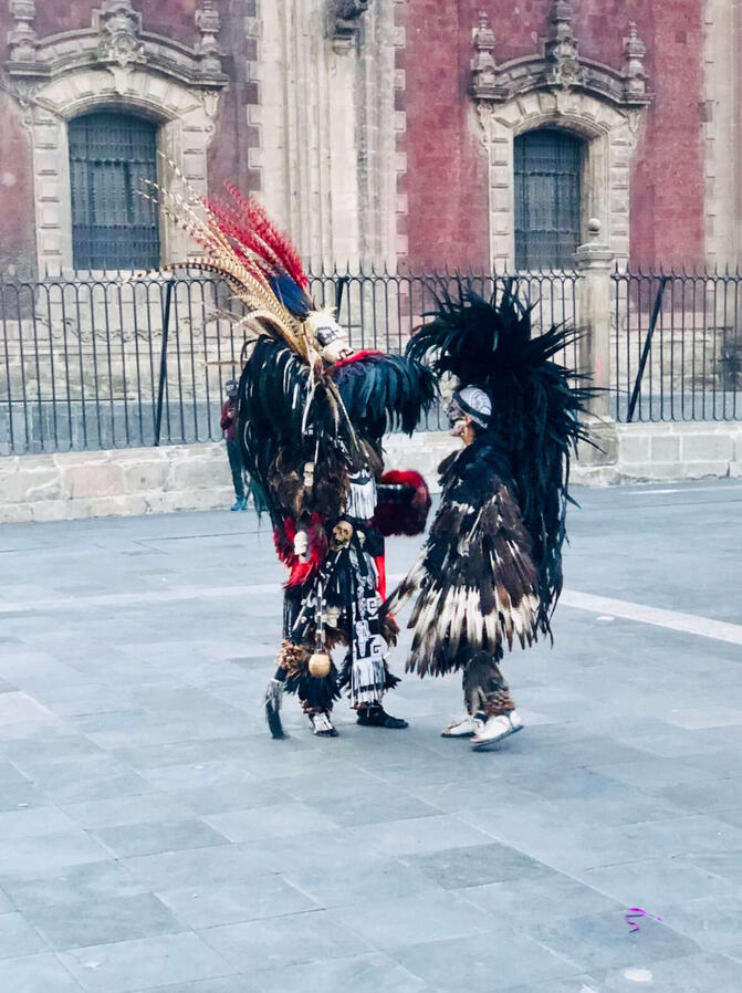 Aztecs Dancers in traditional Aztec ceremonial attire performing in Mexico City's Zocalo square during a cultural walking tour