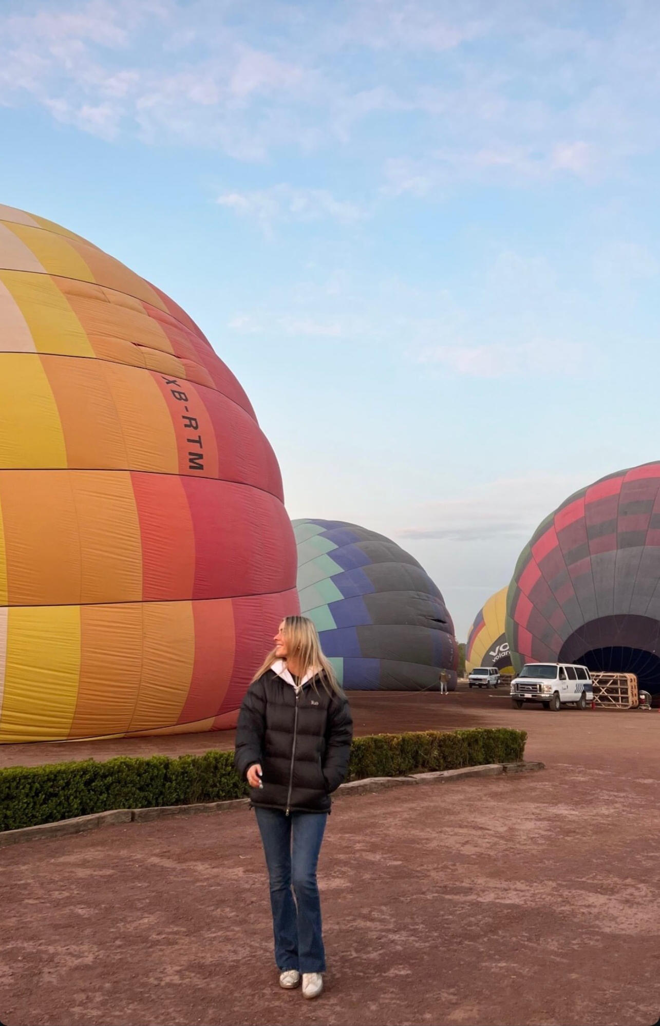 Sunrise Hot Air Balloon Experience A visitor standing before colorful hot air balloons in Mexico City, showcasing an adventurous and scenic highlight of our exclusive travel experiences.