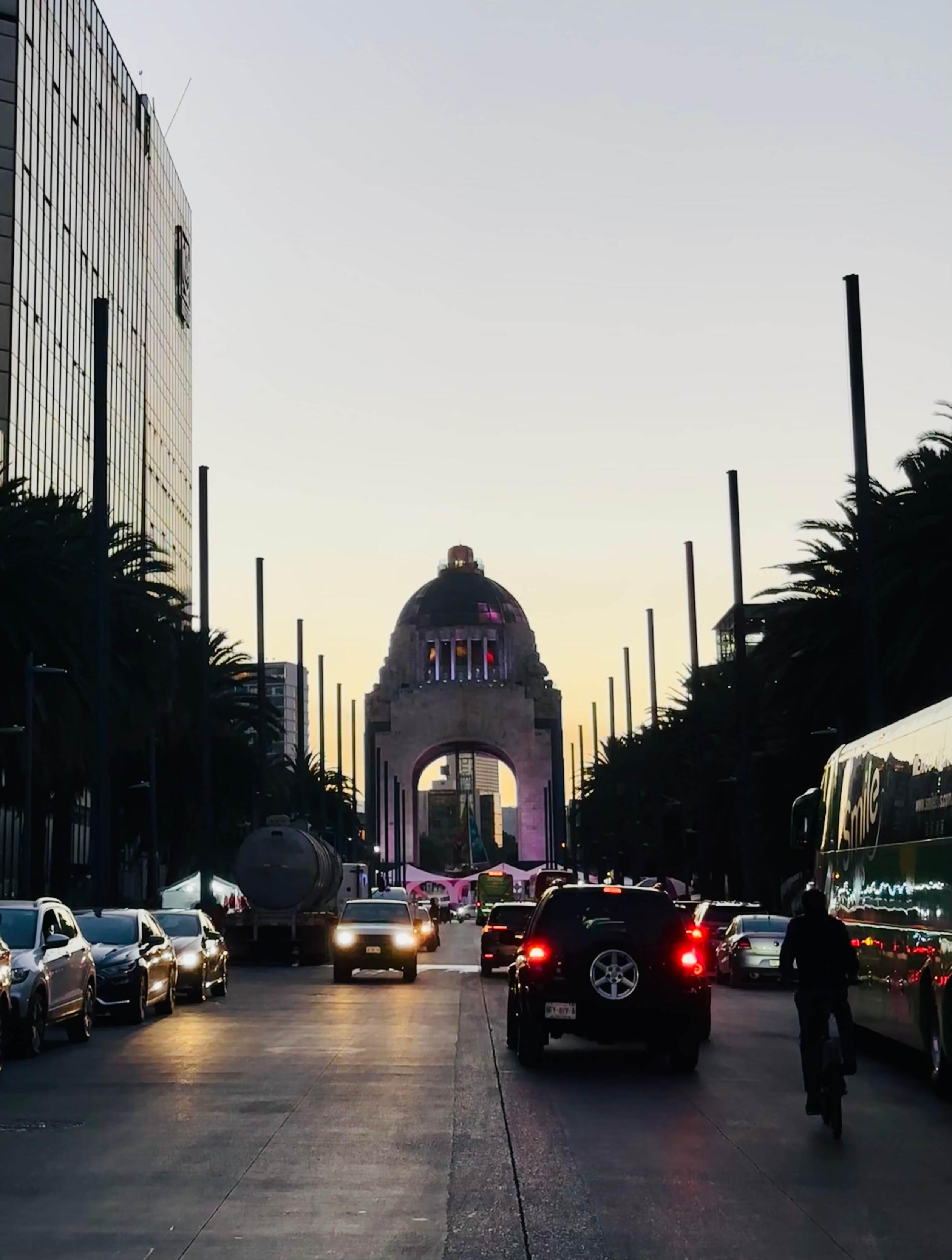 Monumento a la revolucion View of the illuminated Monument to the Revolution at sunset from a Mexico City street during a cultural walking experience.